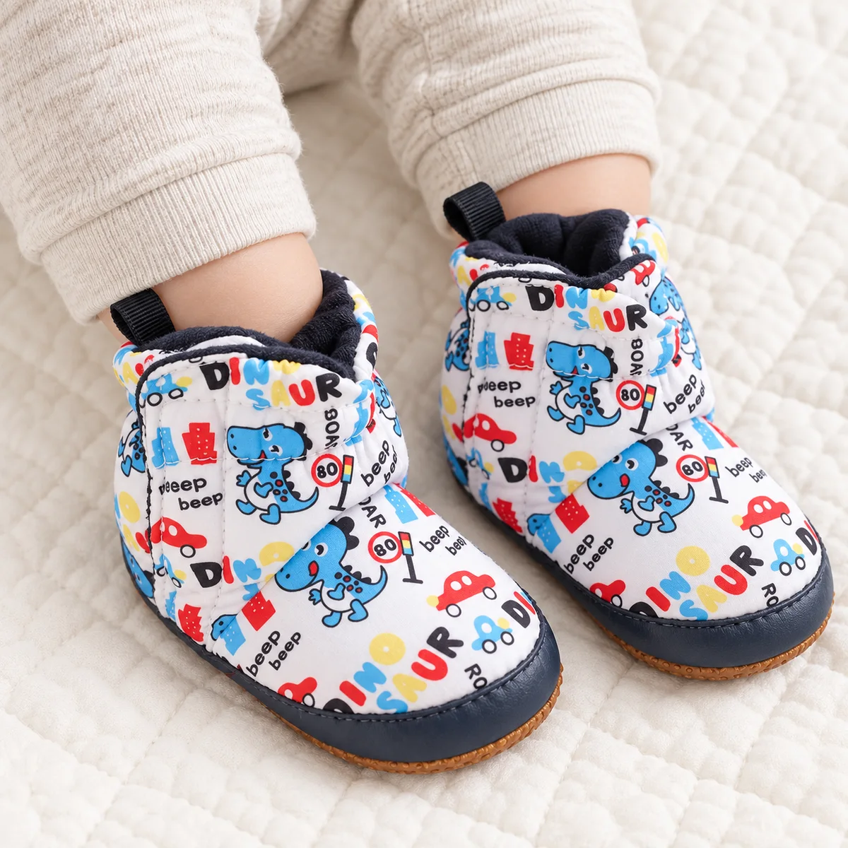 bottines bebe blanches a dinosaures colores et scratch portees par un bebe