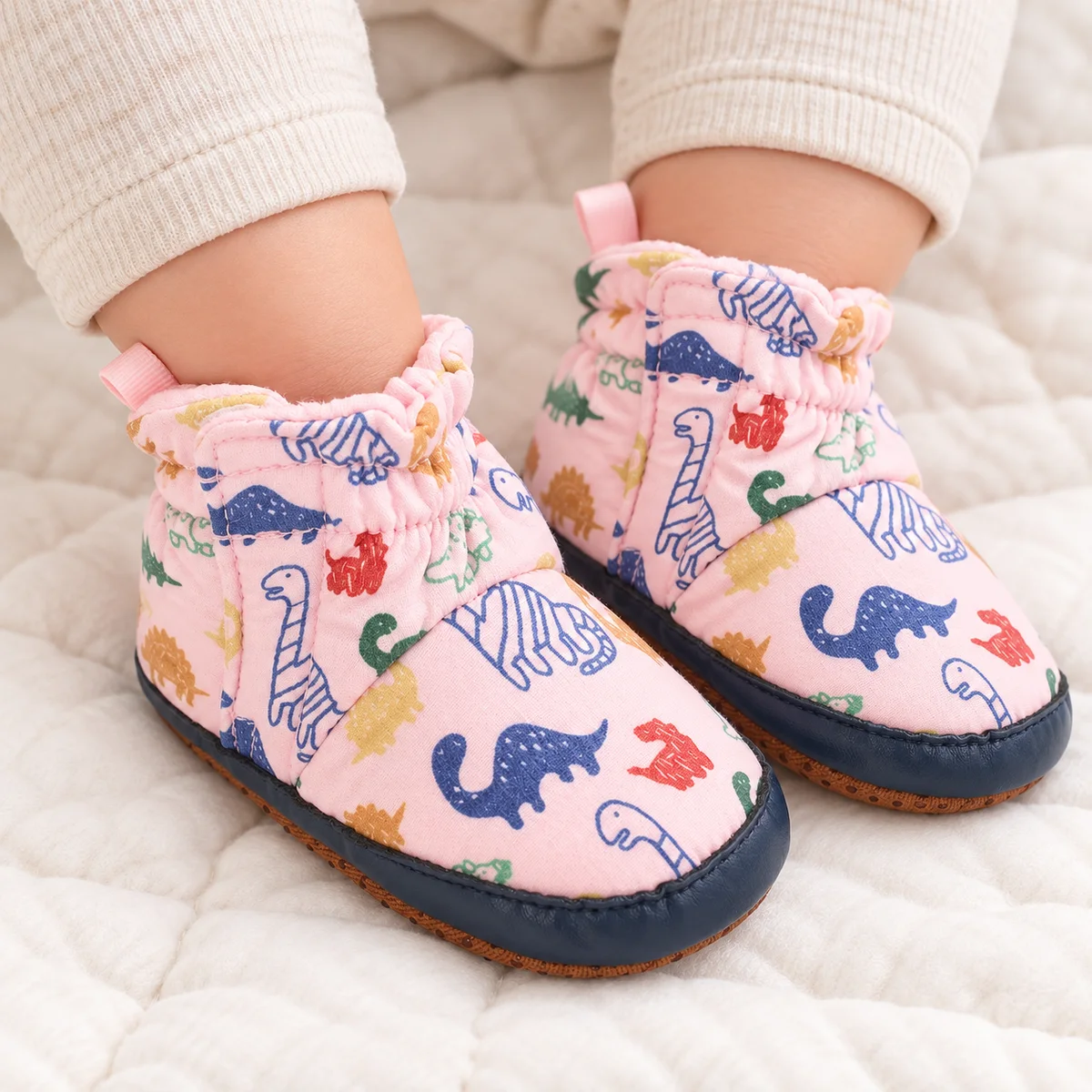 bottines bebe roses a motif dinosaure et scratch portees par un bebe