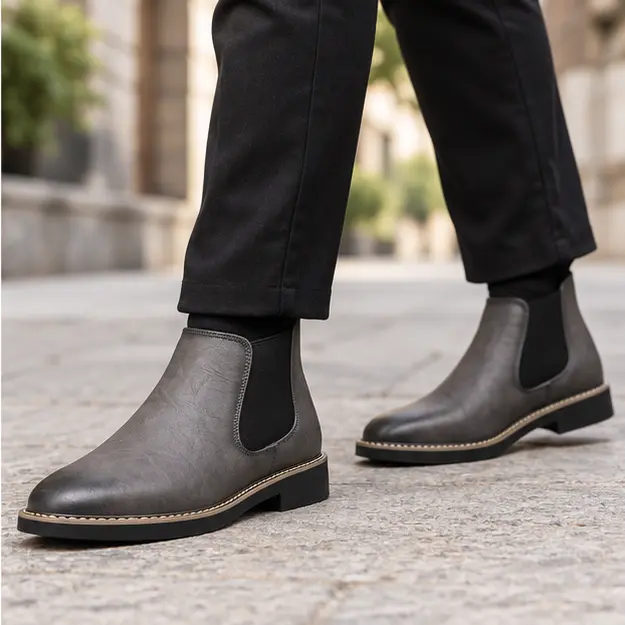 bottines chelsea homme grises a coutures contrastantes portees en marchant avec un pantalon sombre 45320