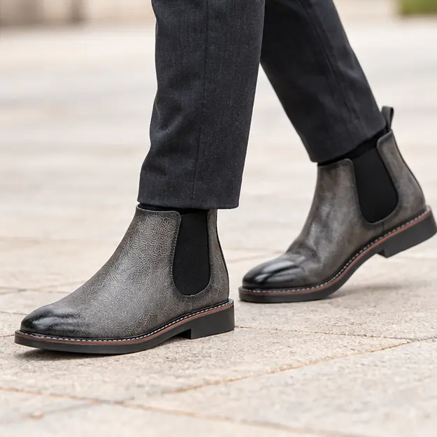 bottines chelsea homme grises a elastiques noirs portees en marchant avec un pantalon sombre 45366