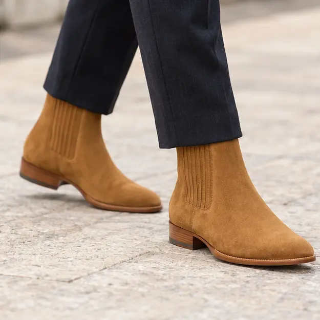 bottines chelsea homme marron clair a bout effile portees en marchant avec un pantalon sombre 45382