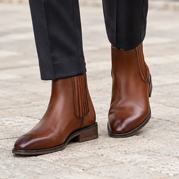 bottines chelsea homme marron clair a semelle epaisse portees en marchant avec un pantalon sombre 45363