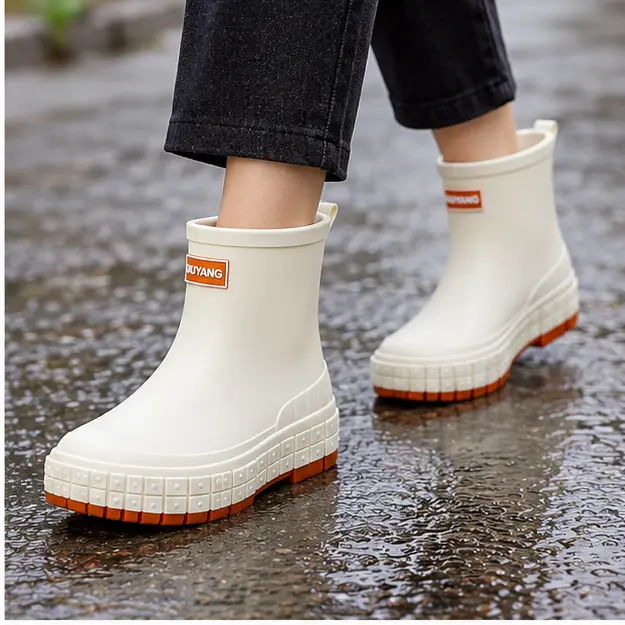 bottines de pluie femme ivoire en caoutchouc portees en marchant avec un pantalon sombre 45186