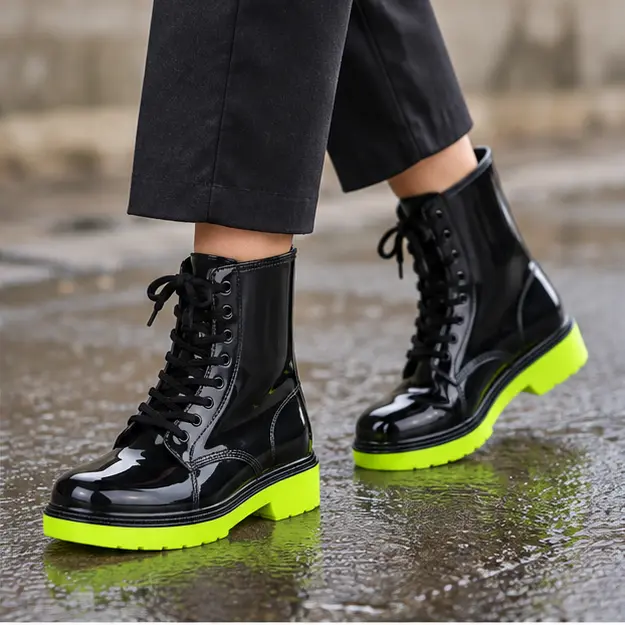 bottines de pluie femme noires et vertes a lacets portees en marchant avec un pantalon sombre 45190