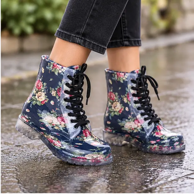 bottines de pluie femme noires fleuries fantaisie portees en marchant avec un pantalon sombre 45199