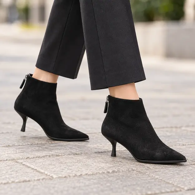 bottines femme noires a petit talon fin portees en marchant avec un pantalon sombre 45152