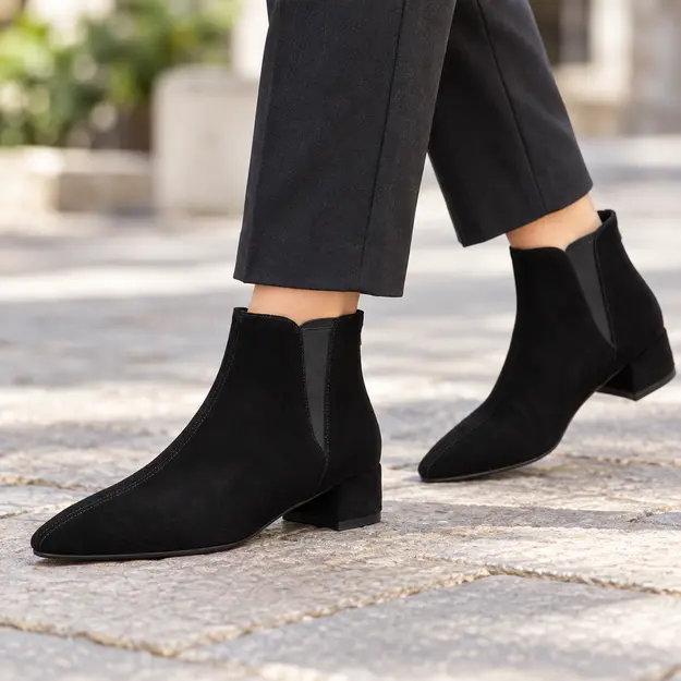 bottines femme noires fourrees a bout effile portees en marchant avec un pantalon sombre 45137