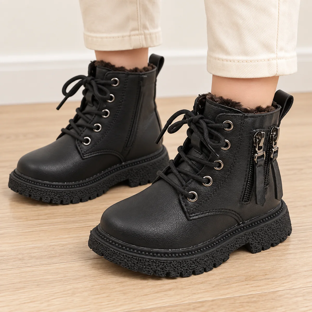 bottines garcon noires fourrees a lacets et zips portees par un enfant
