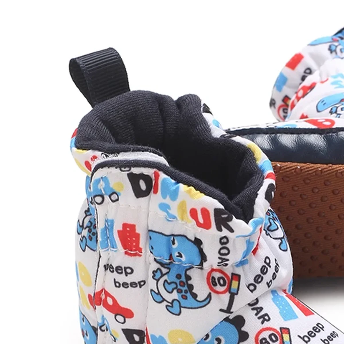 gros plan du haut des bottines bebe blanches a dinosaures colores et scratch
