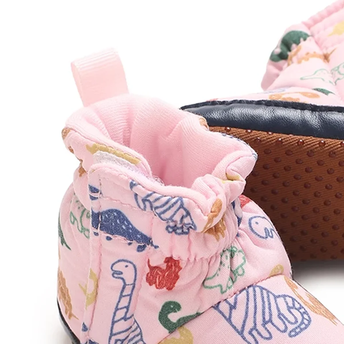 gros plan du haut des bottines bebe roses a motif dinosaure et scratch
