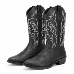 Paire de bottes cowboy noires à arabesques claires sur fond clair.