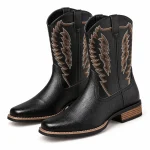 Paire de bottes cowboy noires à broderies en ailes sur fond clair.