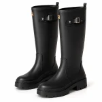 Paire de bottes de pluie noires à boucle latérale sur fond clair.