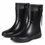 Paire de bottes de pluie noires à col resserrable sur fond clair.