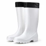 Paire de bottes de pluie blanches fourrées à revers noir sur fond clair.