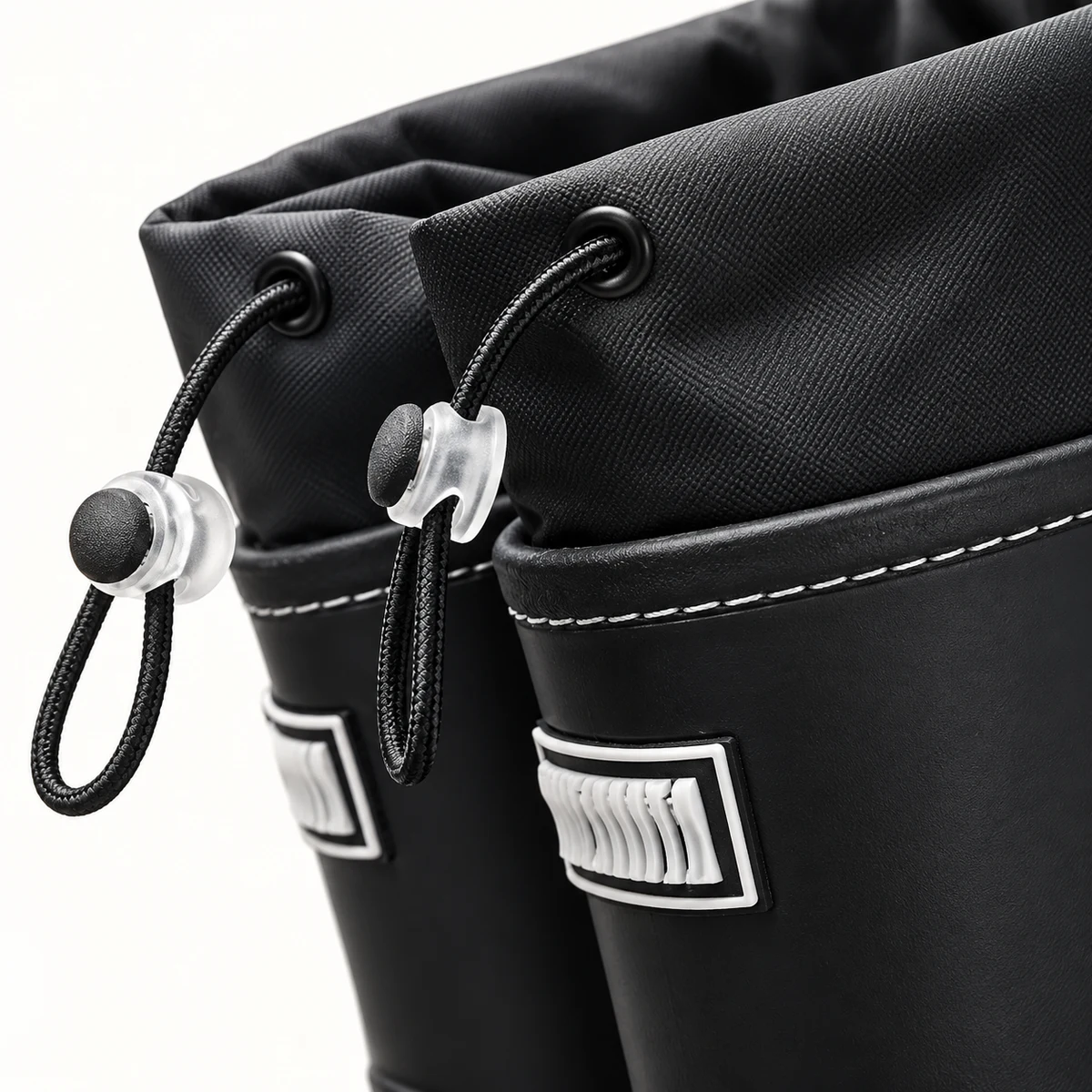Détail des matières et des finitions des bottes de pluie noires à cordon et semelle crantée.