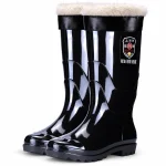 Bottes de pluie noires brillantes à revers noir et doublure claire présentées sur fond blanc.