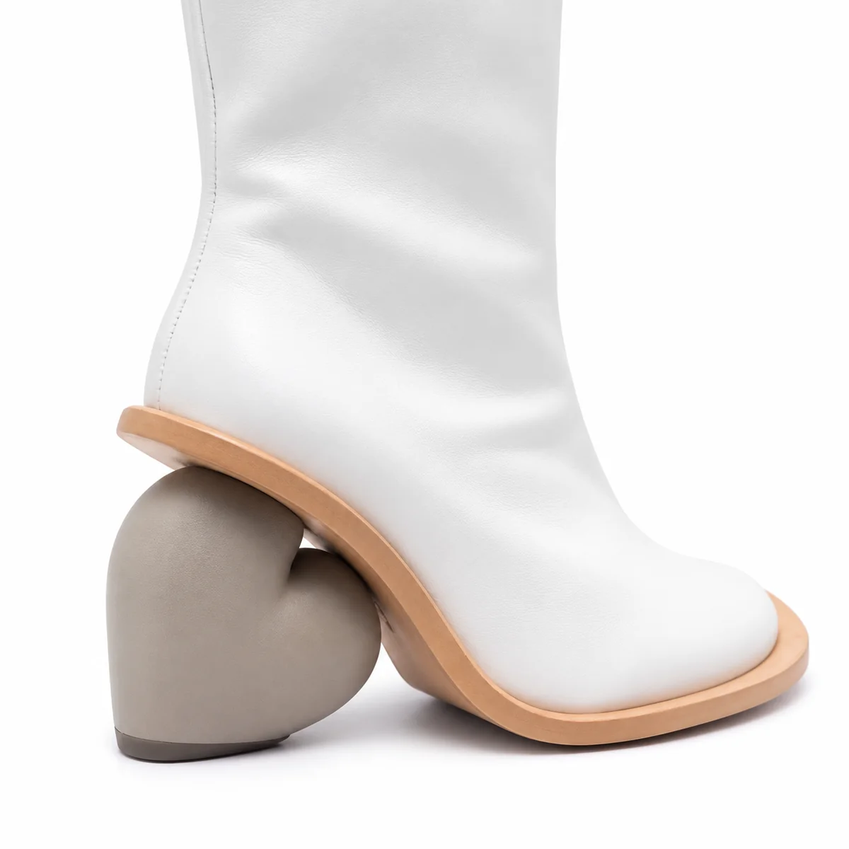 Femme portant des bottes blanches à talon cœur, style moderne et chic