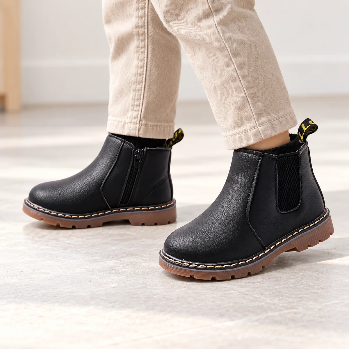 Jeune garçon portant des bottines Chelsea noires à semelle contrastée