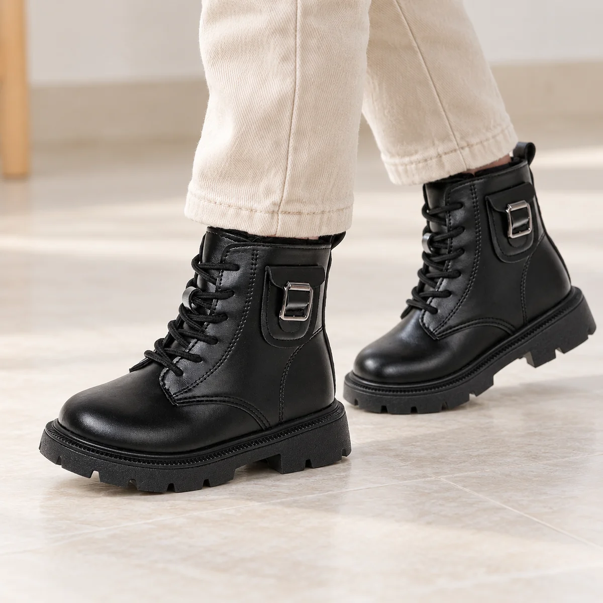 Enfant portant des bottines noires à boucle avec semelle robuste