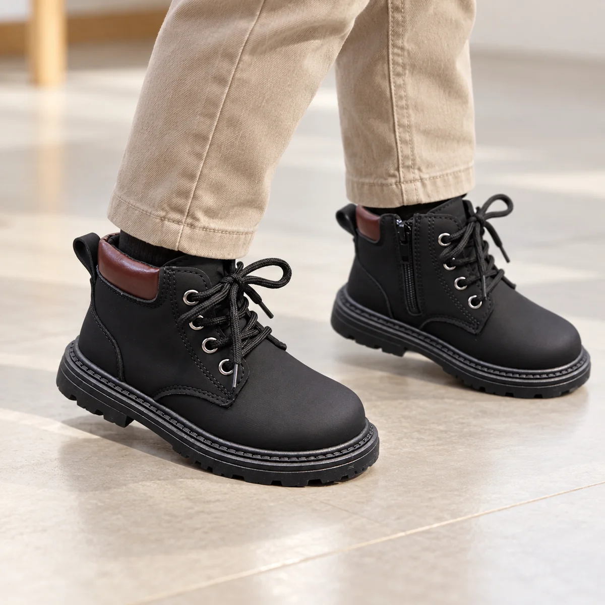 Enfant portant des bottines noires à lacets et coutures blanches dans la rue