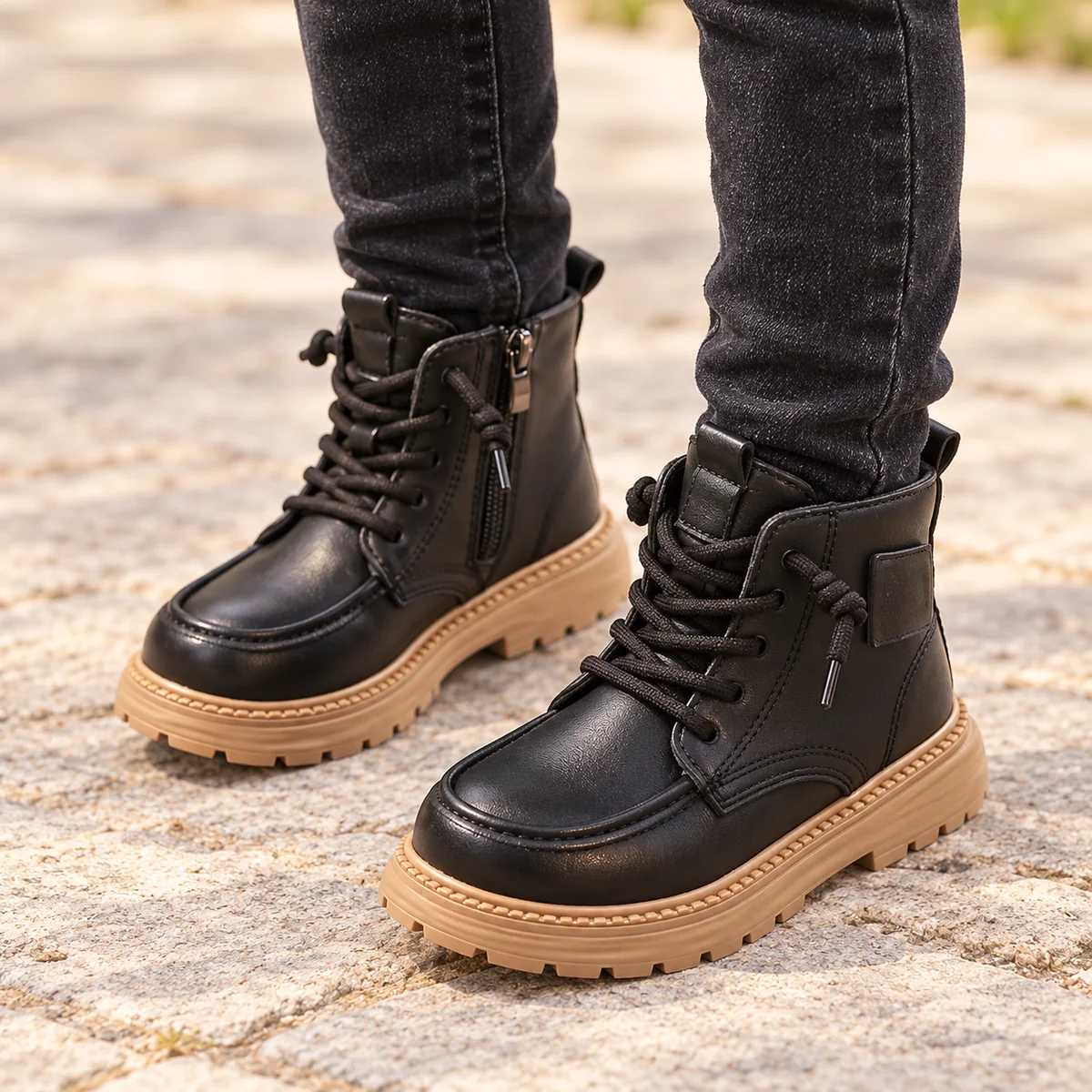 Enfant portant des bottines noires à lacets et semelle beige