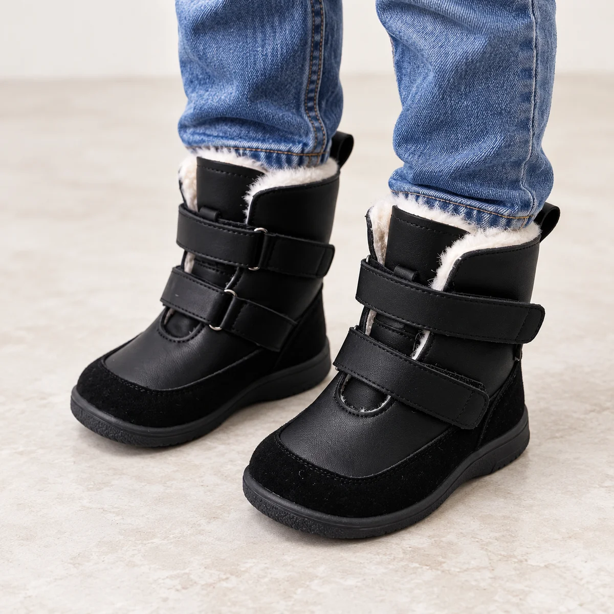 Enfant portant des bottines noires en suédine à scratchs