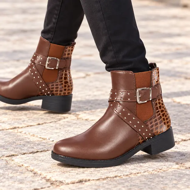 bottines femme cafe a boucles et clous portees en marchant avec un pantalon sombre 45049
