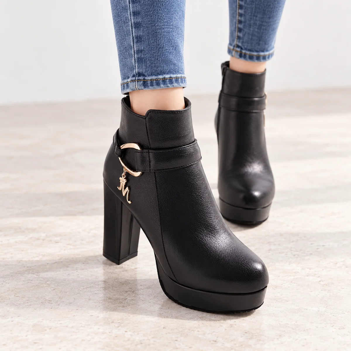 Vue rapprochée de bottines noires à plateforme et détail de l'anneau décoratif