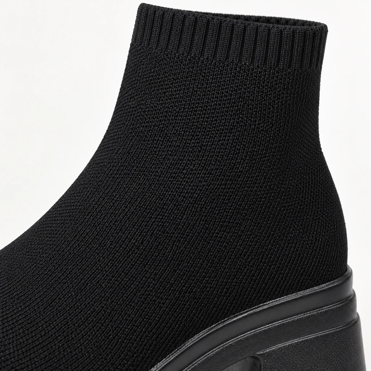 Femme portant des bottines noires à tige côtelée et semelle crantée dans la rue