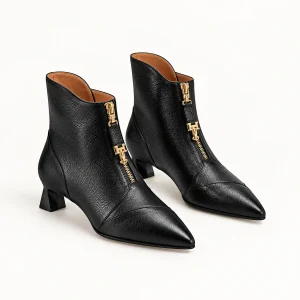 Bottines noires pour femme à bout pointu avec zip doré sur fond blanc