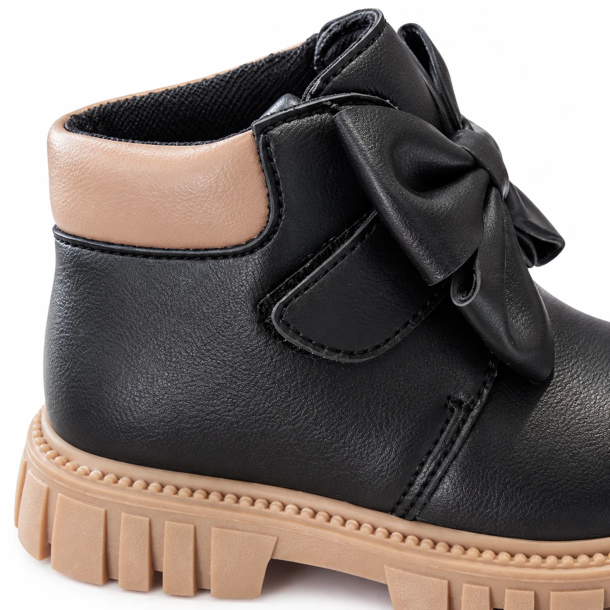 Vue rapprochée des bottines noires pour fille avec nœud et semelle doublée de couleur