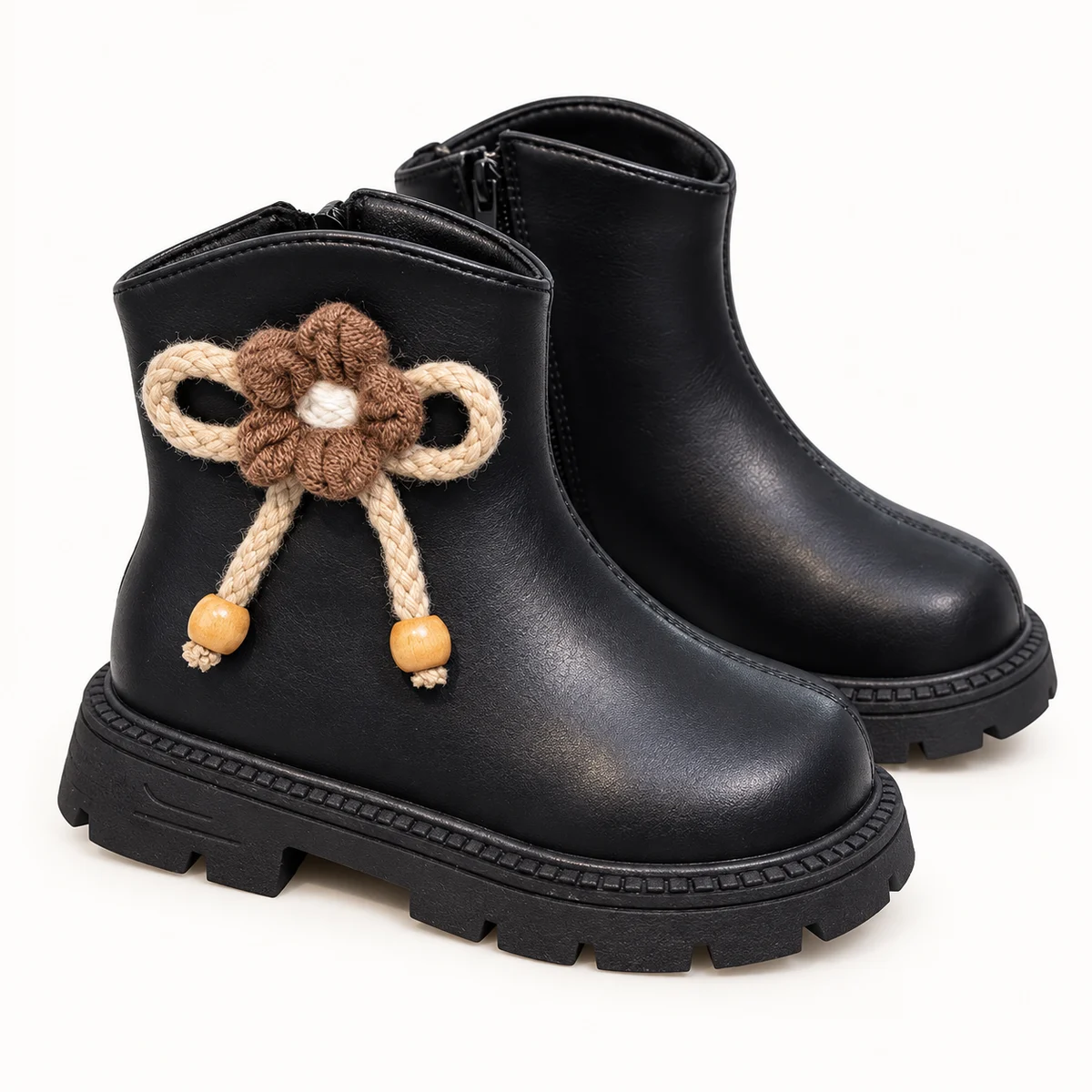 Vue rapprochée des bottines fille noires avec fourrure, fleurs et pompons