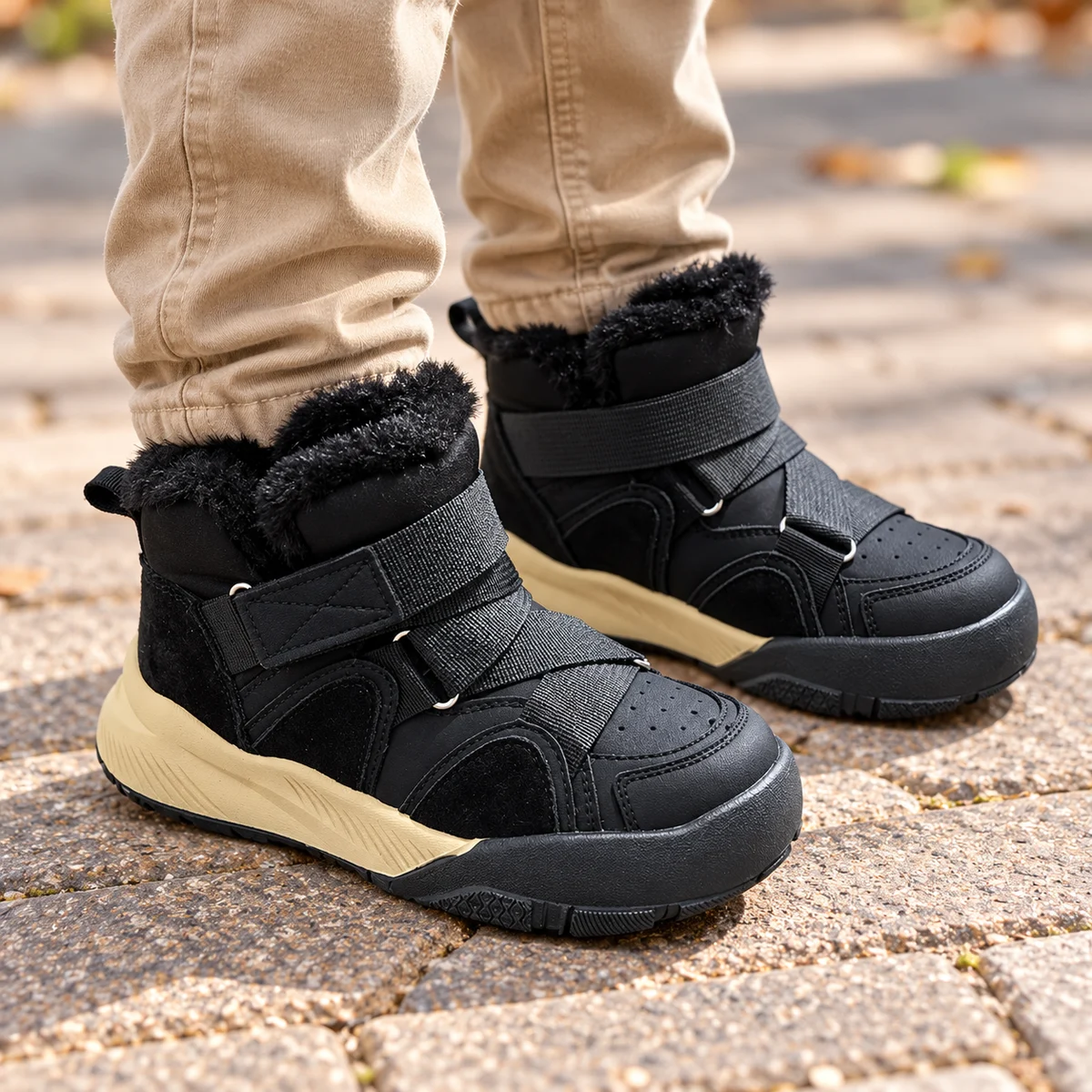 Enfant portant des bottines garçon noires avec scratchs et col fourré