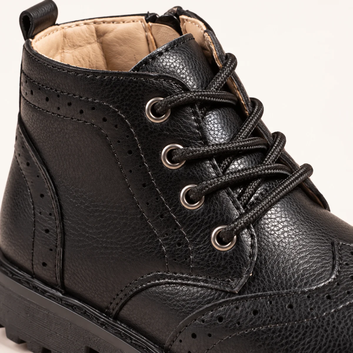 Close-up des bottines garçon noires à semelle crantée et lacets
