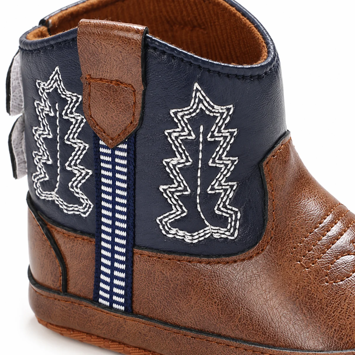 Close-up des bottines western pour bébé fille en tissu brodé bleu marine
